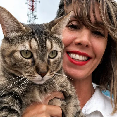 Faby sonriendo con un gato atigrado en brazos