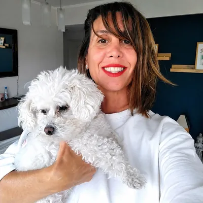 Faby abrazando a un caniche blanco en su casa