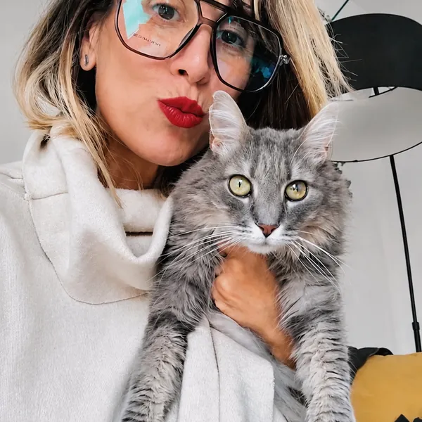 Faby dándole un beso a un gato gris de pelo largo