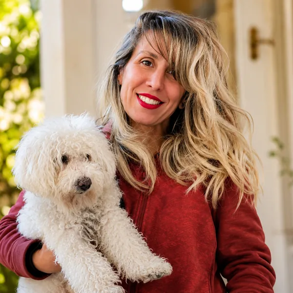 Faby sonriendo con un caniche blanco en brazos